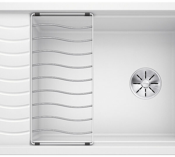 White kitchen sink with built-in draining area on the left and a metal dish rack across the basin.
