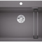 Rectangular dark gray kitchen sink with a round stainless drain in the center and a vertical metal drying rack on the right side inside the basin.