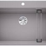 Top-down view of a gray kitchen sink with a circular drain in the center and a fold-out metal drying rack on the right side