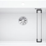 Top-down view of a white rectangular kitchen sink with a metal circular drain and fold-out drying racks on the right side.