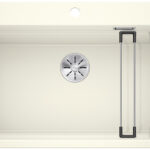 Top-down view of a beige kitchen sink with a round drain in the center and two metal drying racks on the right side.