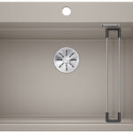 Beige single-basin kitchen sink with a center drain and a built-in drying rack on the right side.