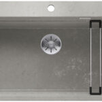Top-down view of a gray kitchen sink with a circular drain and a metal drying rack on the right side.