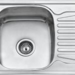 Top-down view of a stainless steel kitchen sink with a curved basin and a built-in draining rack on the right side