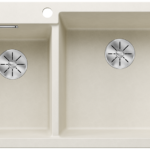 Beige double-basin kitchen sink with two circular metal drains and a faucet hole above the left basin.
