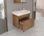 Wooden bathroom vanity with a white sink, wall-mounted faucet, pink soap dispenser, and an open lower drawer showing toiletries.