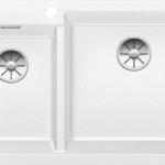 Top-down view of a white double-basin kitchen sink with separate left and right basins and metal drain inserts