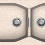 Top-down view of a beige double kitchen sink with two round stainless steel drain baskets beyond a central divider.