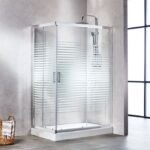 Glass shower enclosure with chrome frame and frosted horizontal stripes, installed on a white shower base in a modern bathroom. A rainfall-style showerhead is mounted above.