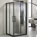 Glass shower enclosure with a black metal frame and sliding doors in a modern bathroom, featuring a built-in shower panel with controls and handheld wand.