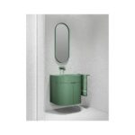 Green oval mirror above a green vanity with a towel in a grey bathroom setting.